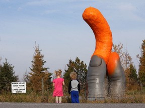 Twins Peyton and Jaxon Physick, 2, stop with their mom to look at the 17-foot-tall Cheetle Hand Statue that stands in the hamlet of Cheadle, Alta.