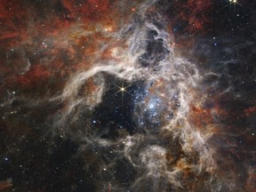 This image released by NASA on Sept. 6, 2022, shows the Tarantula Nebula star-forming region, captured by the James Webb Space Telescope. Stretching 340 light-years across, Webb's Near-Infrared Camera (NIRCam) displays the Tarantula Nebula star-forming region in a new light, including tens of thousands of never-before-seen young stars that were previously shrouded in cosmic dust. THE CANADIAN PRESS/NASA, ESA, CSA, STScl, and Webb ERO Production Team via AP