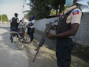 Police officers check motorcycle drivers in Port-au-Prince, Haiti, Saturday, Oct. 15, 2022.