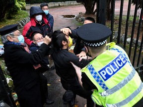 This handout from The Chaser News taken on October 16, 2022 and released to AFP on October 17 shows an incident involving a scuffle between a Hong Kong pro-democracy protester (C) and Chinese consulate staff, as a British police officer attempts to intervene, during a demonstration outside the consulate in Manchester.