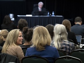 Convoy protest organizer Tamara Lich, left, speaks with a lawyer as Public Order Emergency Commission?s Commissioner Paul Rouleau, top, delivers his opening remarks in Ottawa, October 13, 2022.