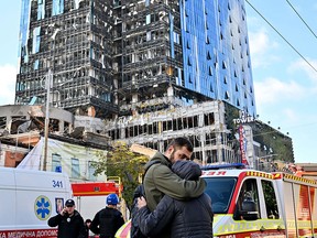 People react outside a partially destroyed multi-storey office building after several Russian strikes hit the Ukrainian capital of Kyiv on Oct. 10, 2022.
