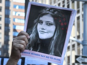 A man holds up a photo of Mahsa Amini