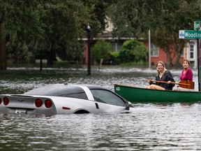 People paddle by in a canoe next to a submerged Chevy Corvette in the aftermath of Hurricane Ian in Orlando, Florida on September 29, 2022. Rain continuted to fall over the weekend, raising concerns of furthe flooding.