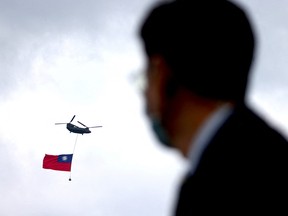 A helicopter carrying Taiwan's flag flies by Taipei during the National Day celebrations in front of the Presidential Office in Taipei, Taiwan on October 10.