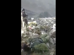 In this frame grab from video that was likely taken by the Taliban and posted online and provided by Afghan Witness, a UK-based open-source nonprofit, a Taliban fighter stands amid bodies on the ground, in the Dara district, of Panjshir province, Afghanistan, Sept. 14, 2022. The Taliban captured, bound and shot to death 27 men in Afghanistan's Panjshir Valley last month during an offensive against resistance fighters in the area, according to a new report by Afghan Witness published Tuesday, Oct. 18, 2022 refuting the group's earlier claims that the men were killed in battle. (Afghan Witness via AP)