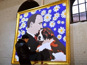 Russian artist Alexey Sergienko puts final touches on his painting 'Putin with a puppy,' dedicated to President Vladimir Putin's upcoming 70th birthday, in Saint Petersburg on Oct. 6.