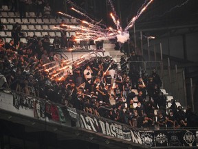 FILE - Fireworks thrown by Marseille supporters explode next to Frankfurt supporters prior to the Champions League group D soccer match between Marseille and Frankfurt at the Velodrome stadium in Marseille, southern France, Tuesday, Sept. 13, 2022. A supporter of French club Marseille has been handed preliminary charges including attempted murder for allegedly firing a flare that seriously injured a visiting German fan during crowd violence at Stade Velodrome last month.