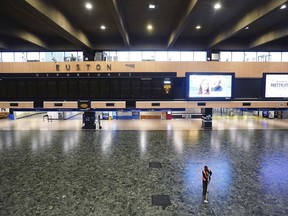 A person sweeps the floor in front of an empty departures board at Euston station, as members of the drivers' union Aslef and the Transport Salaried Staffs Association (TSSA) go on strike, in London, Wednesday, Oct. 5, 2022.