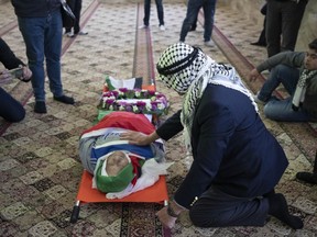 FILE - Mourners take a last look at the body of Omar Asaad, 78, during his funeral at a mosque in the West Bank village of Jiljiliya, north of Ramallah, Jan. 13, 2022. Israel said Sunday, Oct. 9, 2022, that it reached a settlement to compensate Asaad's family who died earlier this year after he was detained by Israeli troops at a checkpoint in the occupied West Bank, binding his hands and blindfolding him. He was left face-down in an abandoned building after they unbound his hands where he was later found unconscious and pronounced dead.