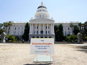 FILE - A sign about saving water is posted on browning grass outside the state Capitol in Sacramento, Calif., on Monday, July 11, 2022. California began its new water year on Oct. 1, 2022, and state officials are expecting another dry winter ahead.