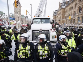 Police hang off a truck as authorities work to end a protest against COVID-19 measures that had grown into a broader anti-government demonstration and occupation lasting for weeks, in Ottawa, Saturday, Feb. 19, 2022.&ampnbsp;The head of Ontario Provincial Police is defending comments he made about the "Freedom Convoy" posing a threat to national security.