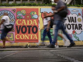 FILE - People walk past a mural that reads in Portuguese: "Every vote counts" in Sao Paulo, Brazil, Oct. 25, 2022. In a last-minute effort to win reelection on Sunday, Oct. 30, Marcos Rocha, the governor of Rondonia, in the Brazilian Amazon and a staunch ally of far-right President Jair Bolsonaro, revoked the protection of a large swath of the Amazon forest.