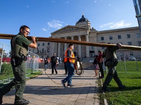Legislative security officers, conservation officers supported by Winnipeg police, move to evict a camp on the north side of the Manitoba legislature grounds in Winnipeg, Tuesday, Oct. 4, 2022. Police say four men and one woman are charged with obstructing a peace officer and occupying a structure in the legislative precinct.