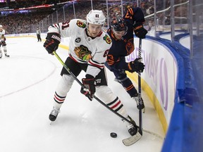 Chicago Blackhawks' Riley Stillman (61) and Edmonton Oilers' Jesse Puljujarvi (13) battle for the puck during first period NHL action in Edmonton on Saturday, November 20, 2021.THE CANADIAN PRESS/Jason Franson