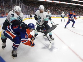 Seattle Kraken' Will Borgen (3) checks Edmonton Oilers' Dylan Holloway (55) as Matty Beniers (10) looks for the puck during second period NHL pre-season action in Edmonton on Friday, October 7, 2022.THE CANADIAN PRESS/Jason Franson