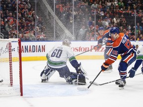 Vancouver Canucks goalie Collin Delia (60) is scored on by Edmonton Oilers' Tyson Barrie (22) as Dylan Holloway (55) watches the puck go in the net during second period preseason action in Edmonton on Monday, October 3, 2022.THE CANADIAN PRESS/Jason Franson