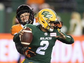 B.C. Lions' Mathieu Betts (90) grabs the face mask of Edmonton Elks quarterback Tre Ford (2) during first half CFL action in Edmonton, Alta., on Friday October 21, 2022.