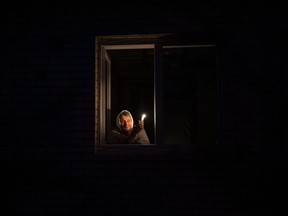 Catherine, 70, looks out the window while holding a candle for light inside her house during a power outage, in Borodyanka, Kyiv region, Ukraine, Thursday, Oct. 20, 2022. Airstrikes cut power and water supplies to hundreds of thousands of Ukrainians on Tuesday, part of what the country's president called an expanding Russian campaign to drive the nation into the cold and dark and make peace talks impossible.