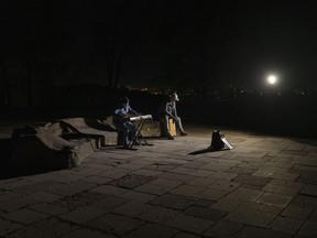 Street musicians play their instruments in a square without electric lights in Kyiv, Ukraine, Tuesday, Oct. 18, 2022.