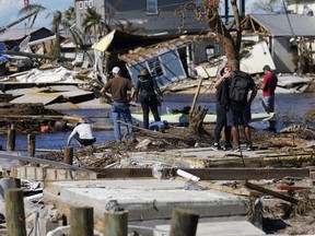 People stand on the destroyed bridge to Pine Island as they view the damage in the aftermath of Hurricane Ian in Matlacha, Fla., Sunday, Oct. 2, 2022. The only bridge to the island is heavily damaged so it can only be reached by boat or air.