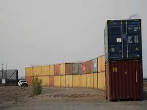 FILE - Border Patrol agents patrol along a line of shipping containers stacked near the border on Aug. 23, 2022, near Yuma, Ariz. The Cocopah Indian Tribe is welcoming the federal government's call for the state of Arizona to remove a series of double-stacked shipping containers placed along the U.S.-Mexico border near the desert city of Yuma, saying they are unauthorized and violate U.S. law.