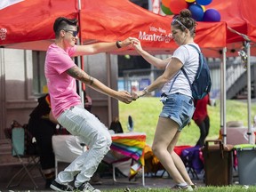 Florence, left, and Billie dance at the site where the Montreal Pride parade was supposed to start from in Montreal, Sunday, August 7, 2022. A new report says communication problems and a simple 'misunderstanding' are at the heart of the decision to cancel Montreal's Pride parade only hours before it was scheduled to begin.