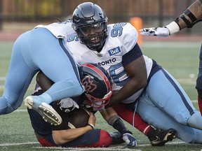 Montreal Alouettes quarterback Trevor Harris, bottom, is brought down by Toronto Argonauts' Sam Acheampong (96) during first half CFL football action in Montreal, Saturday, October 22, 2022.