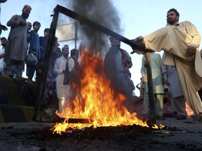 Supporters of former Prime Minister Imran Khan's party burn tires and other stuff as they block a road during a protest to condemn election commission's decision, Friday, Oct. 21, 2022, in Peshawar, Pakistan. Officials say Pakistan's elections commission has disqualified former Prime Minister Imran Khan from holding public office for five years, after finding he had unlawfully sold state gifts and concealed assets as premier.