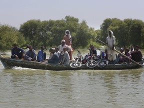 Villagers with their belongings cross a flooded area on a boat, in Dadu, a district of southern Sindh province, Pakistan, Sept. 23, 2022. The devastation wreaked by floods in Pakistan this summer has intensified the debate over a question of climate justice: Do rich countries whose emissions are the main cause of climate change owe compensation to poor countries hit by climate change-fueled disasters?
