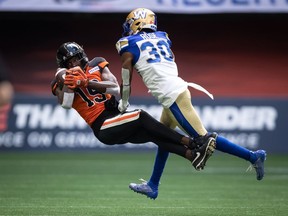B.C. Lions' Dominique Rhymes, left, makes a reception as Winnipeg Blue Bombers' Winston Rose defends during the first half of CFL football game in Vancouver, on July 9, 2022.