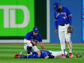 Toronto Blue Jays centre fielder George Springer, lays on the field after being injured on a three-RBI double off the bat of Seattle Mariners shortstop J.P. Crawford (3) as Santiago Espinal, left, and Teoscar Hernandez look on during eighth inning American League wild card MLB postseason baseball action in Toronto on Saturday, October 8, 2022.