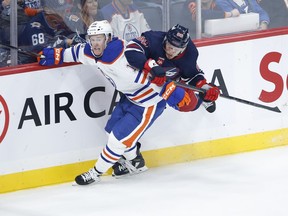Winnipeg Jets' Nate Schmidt (88) and Edmonton Oilers' Tyler Benson (16) collide along the boards during second period pre-season NHL action in Winnipeg, Saturday, October 1, 2022.