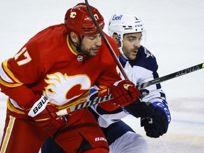 Winnipeg Jets defenceman Dylan DeMelo, right, checks Calgary Flames forward Milan Lucic during second period NHL pre-season hockey action in Calgary, Friday, Oct. 7, 2022.&ampnbsp;Calgary Flames winger Milan Lucic reached a career 1,100 NHL games played Thursday with a live audience on hand for that milestone.