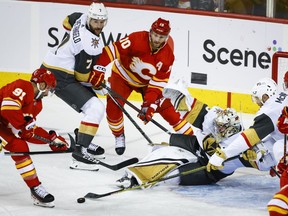 Vegas Golden Knights goalie Logan Thompson, centre, scrambles to block the net as Calgary Flames' Nazem Kadri, left, and Jonathan Huberdeau, third left, chase the puck while Golden Knights' Alex Pietrangelo, second left, defends during second period NHL hockey action in Calgary, Tuesday, Oct. 18, 2022.THE CANADIAN PRESS/Jeff McIntosh