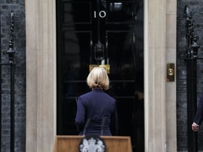 Liz Truss, followed by her husband Hugh O'Leary, right, walks back into 10 Downing Street after making a statement where she announced her resignation as Prime Minister, in London, Thursday Oct. 20, 2022. Truss resigned Thursday, bowing to the inevitable after a tumultuous, short-lived term in which her policies triggered turmoil in financial markets and a rebellion in her party that obliterated her authority.