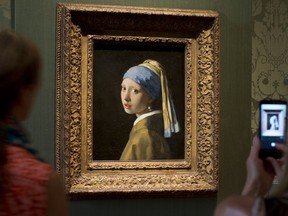 FILE- Visitors take pictures of Johannes Vermeer's Girl with a Pearl Earring (approx. 1665) during a preview for the press of the renovated Mauritshuis in The Hague, Netherlands, June 20, 2014. The Vermeer masterpiece "Girl with a Pearl Earring" has become the latest artwork targetted by climate activists in a protest at the Mauritshuis museum in The Hague on Thursday, Oct. 27, 2022. The museum did not immediately return calls and emails for comment after a video of the protest was posted on Twitter.