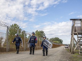 FILE - Operational police officers walk along the service route of Hungary's border with Serbia near Roszke, Southern Hungary, Wednesday, Sept. 28, 2022. The leaders of Hungary, Austria and Serbia met Monday in Budapest to find solutions on how to stem the recently increasing number of migrants arriving in Europe.