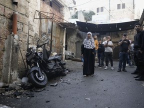 Palestinians gather around the motorcycle that Palestinian militant group Den of Lions says was planted with an explosive device, killing one of its top fighters, Tamer al-Kilani, as he walked past, in the Old City of Nablus in the West Bank, Sunday, Oct. 23, 2022. The Den of Lions has accused Israel of killing one of its top fighters in a targeted attack deep inside the West Bank city and promised to unleash a fierce response. The Israeli military declined to comment.