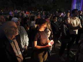 Marie Crane, center, holds a candle during a vigil in Tower Grove Park for the victims of a school shooting at Central Visual & Performing Arts High School in St. Louis on Monday, Oct. 24, 2022.