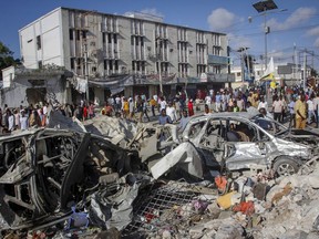 People walk amidst destruction at the scene, a day after a double car bomb attack at a busy junction in Mogadishu, Somalia Sunday, Oct. 30, 2022. Somalia's president says multiple people were killed in Saturday's attacks and the toll could rise in the country's deadliest attack since a truck bombing at the same spot five years ago killed more than 500.
