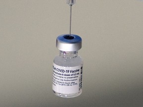 FILE - A syringe is placed into a vial of Pfizer-BioNTech vaccination at a COVID-19 clinic in Augusta, Maine, on Tuesday, Dec. 21, 2021. On Thursday, Oct. 20, 2022, Pfizer said it will charge $110 to $130 for a dose of its COVID-19 vaccine once the U.S. government stops buying the shots, but the drugmaker says it expects many people will continue receiving doses for free.