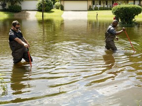 FILE - Hinds County Emergency Management Operations deputy director Tracy Funches, right, and operations coordinator Luke Chennault, wade through flood waters in northeast Jackson, Miss., on Aug. 29, 2022, as they check water levels. A federal agency has set aside money to help guard Mississippi's capital city and surrounding areas against flood damage following two deluges in three years. The U.S. Army Corps of Engineers announced Monday, Oct. 3, 2022, that it has budgeted $221 million to help fund a local flood-control project.