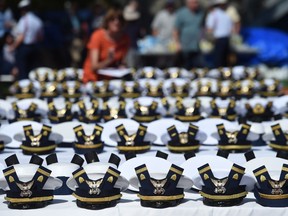 FILE - The new hats and shoulder bars for the graduates sit on a table before the start of the U.S. Coast Guard Academy's 141st Commencement Exercises, May 18, 2022, in New London, Conn. A U.S. Coast Guard Academy cadet who was expelled for becoming a father will get his degree as part of a legal settlement, his attorneys said Thursday, Oct. 6, 2022.