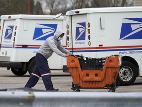 FILE - A U.S. Postal Service employee works outside a post office in Wheeling, Ill., Dec. 3, 2021. A federal judge has set limits on one of the U.S. Postal Service's cost-cutting practices that contributed to a worrisome slowdown of mail deliveries ahead of the 2020 presidential election.
