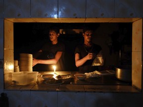 Staff at an eatery work by candle light after a failure in Bangladesh's national power grid plunged much of the country into a blackout in Dhaka, Bangladesh, Tuesday, Oct.4, 2022.