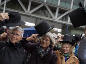 Campaigners take their hat off in a show of respect for people who took their own lives in The Hague, Netherlands, Monday, Oct. 10, 2022, where they calling for the decriminalization of assisted suicide in the Netherlands took the Dutch state to court, arguing its ban breaches human rights norms. The case at The Hague District Court was brought by a group called Cooperative Last Will, which has long urged a change of the law to allow people to help relatives end their lives.