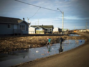 Indigenous children play in water-filled ditches in Attawapiskat, Ont.