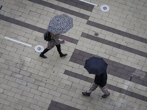 Pedestrians carry umbrellas as light rain falls in Surrey, B.C., on Friday, October 21, 2022. BC Hydro says electricity has been restored to most of its more than 100,000 customers blacked out during the first powerful storm of British Columbia's late-arriving fall, but forecasters warn more foul weather is on the way.