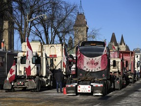 A person walks among trucks on Wellington Street on the 18th day of a protest against COVID-19 measures that has grown into a broader anti-government protest, in Ottawa, on Monday, Feb. 14, 2022.